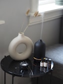 a white vase sitting on top of a black table