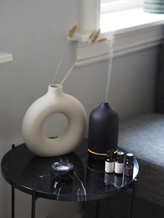 a white vase sitting on top of a black table