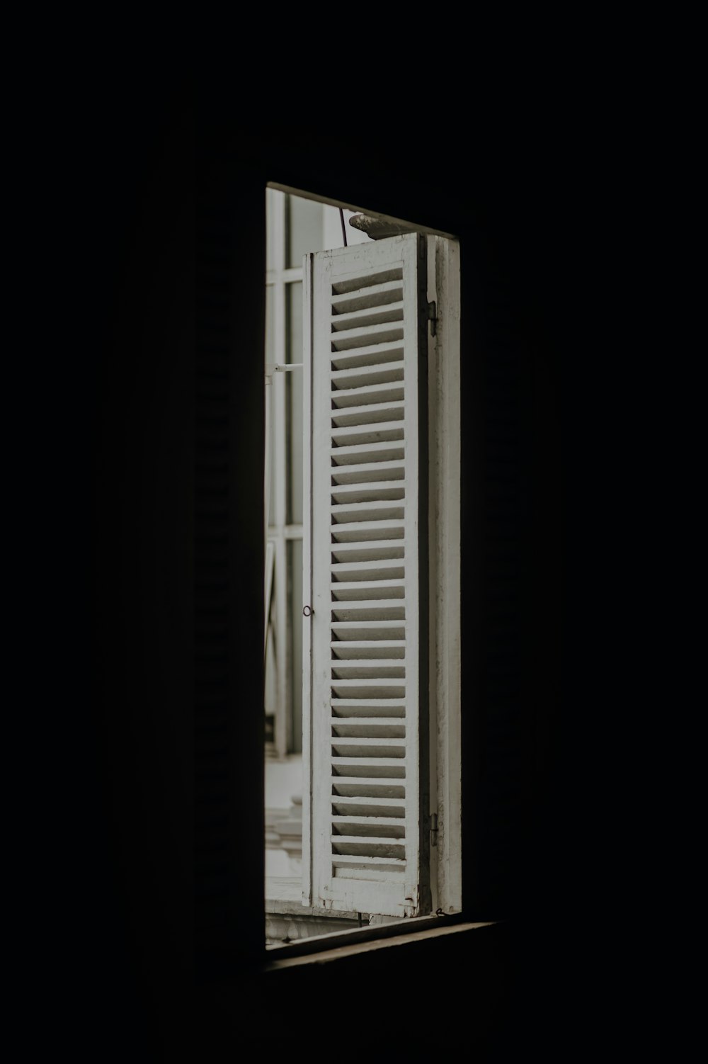 a window in a dark room with shutters open
