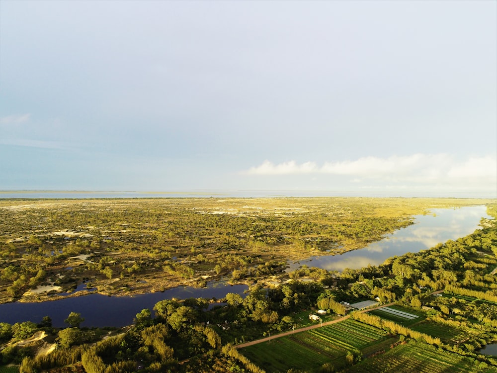 an aerial view of a river running through a lush green field