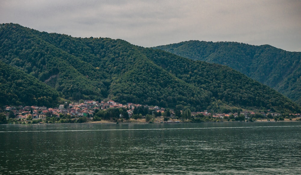 a small boat floating on top of a lake next to a lush green hillside