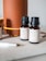 Several small brown bottles with black caps are placed on a light surface near a large orange cylindrical diffuser. The labels on the bottles describe different essential oil blends, such as 'Energy', indicating scents like lime and grapefruit. A white pen is visible in the foreground.