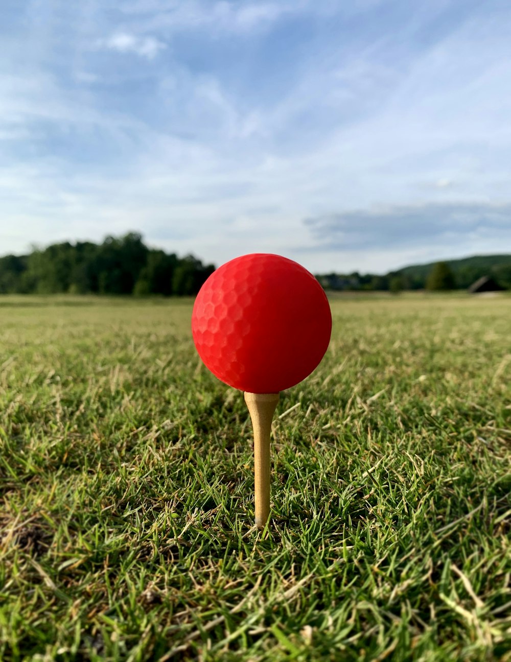a red golf ball sitting on top of a wooden tee