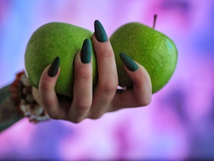 a woman holding two green apples in her hands