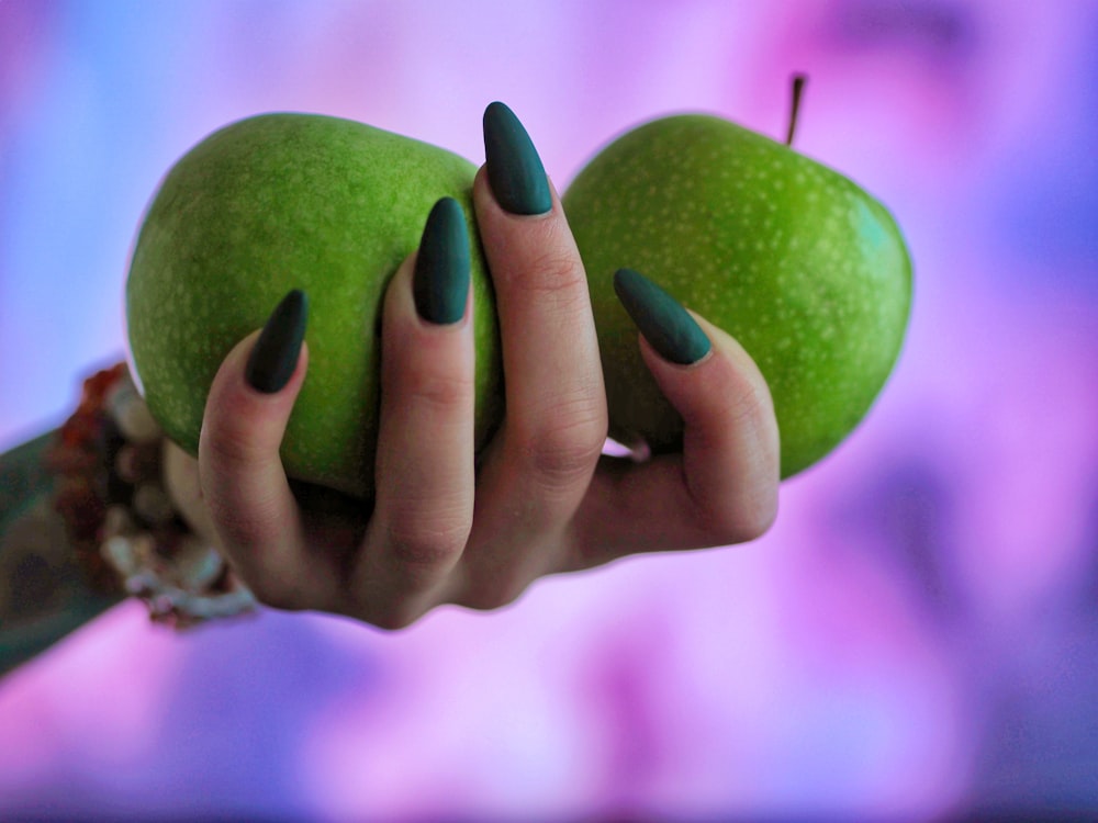 a woman holding two green apples in her hands