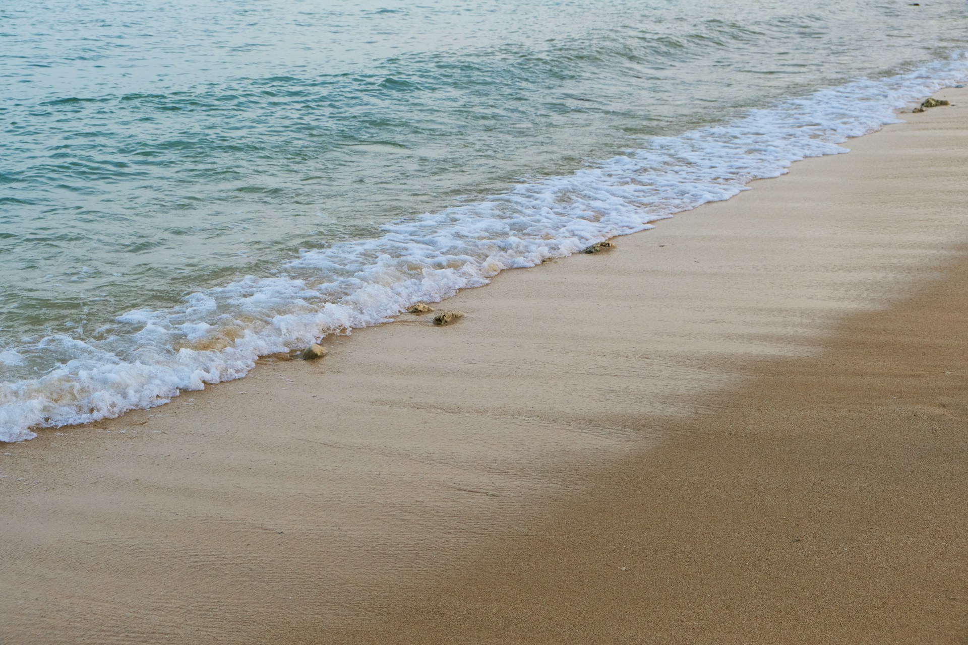 a sandy beach with waves coming in to shore