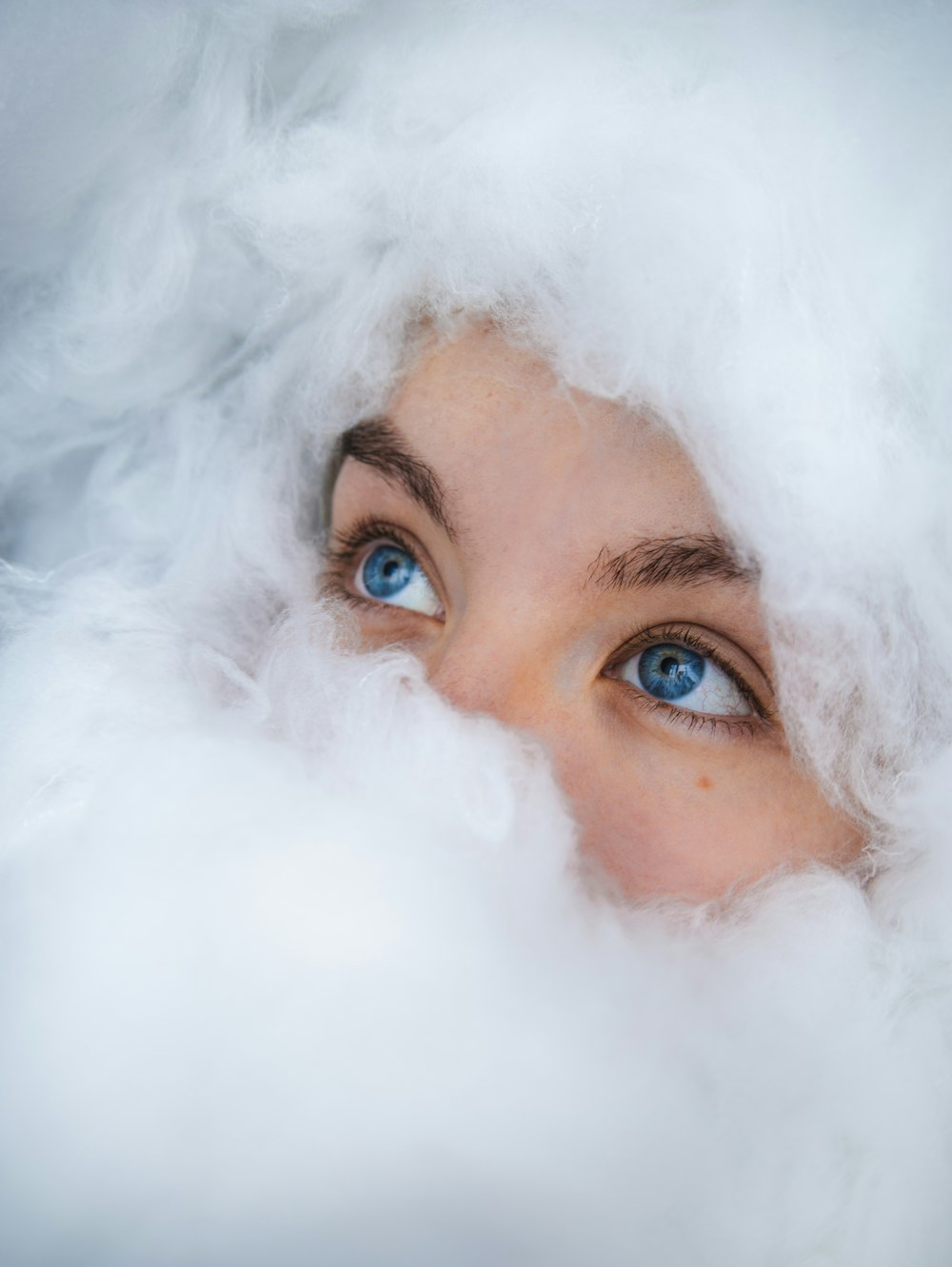 a woman with blue eyes peeking out from a cloud