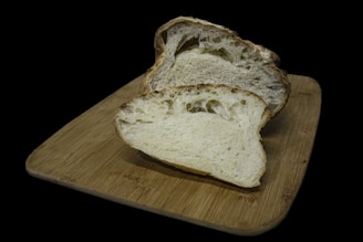 A rustic wooden board displaying freshly baked artisan bread with a crispy crust and soft interior.