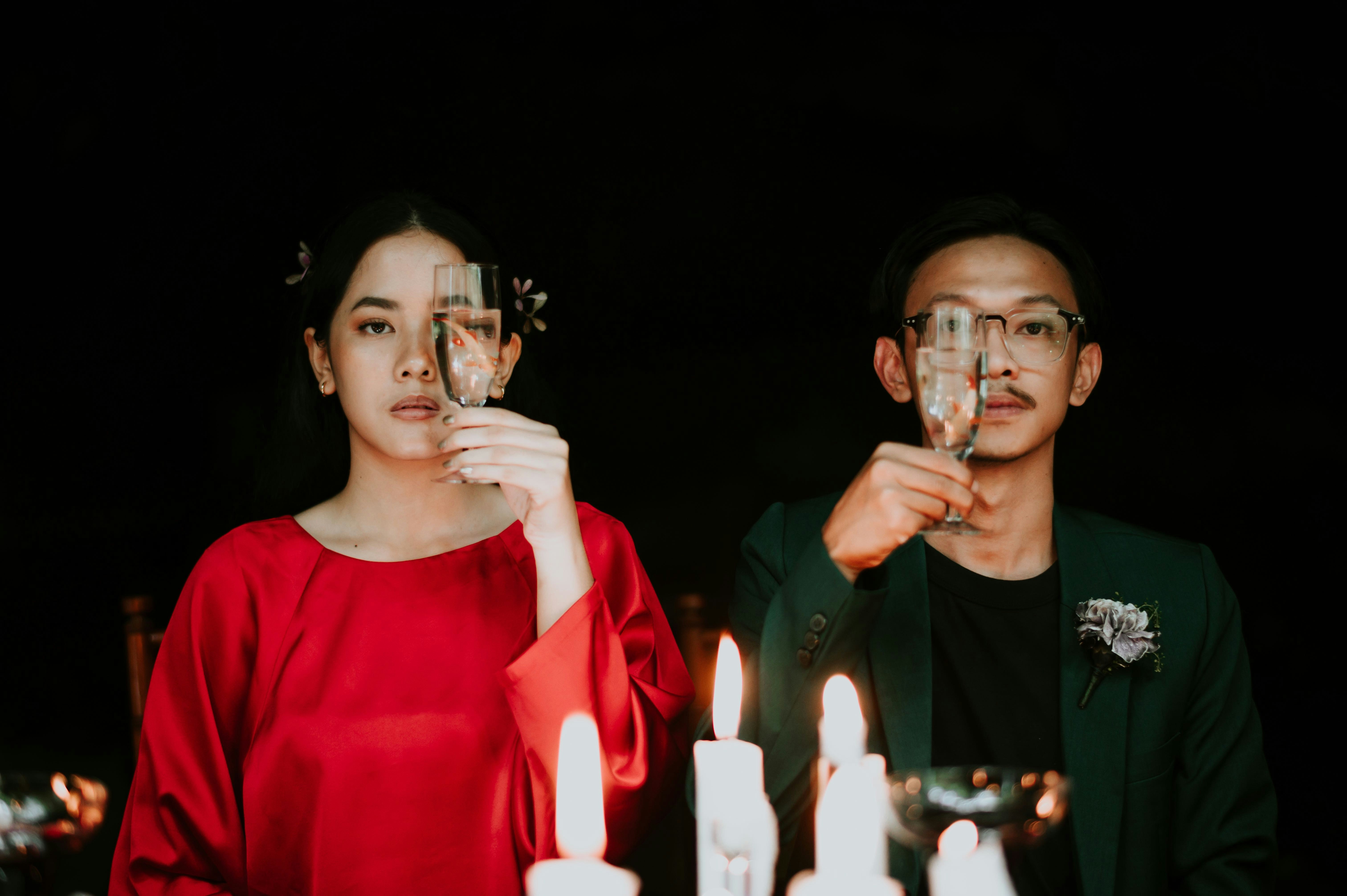 Seorang pria dan seorang wanita memegang gelas anggur di depan kue