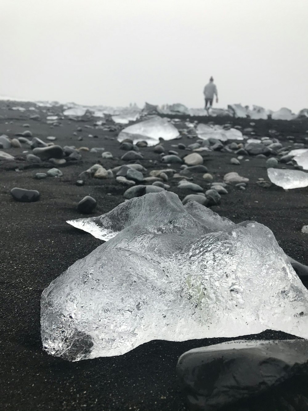 a man standing on top of a black sand beach