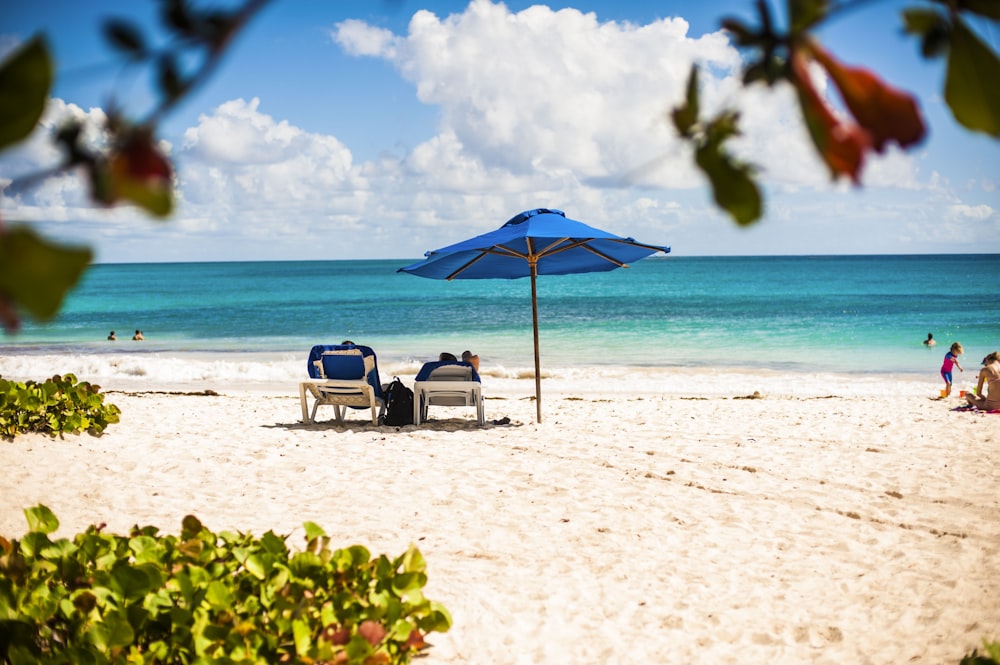 a couple of lawn chairs sitting on top of a sandy beach