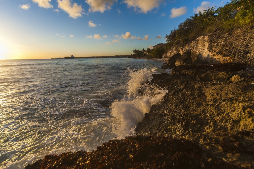 the sun is setting over the ocean with waves crashing on the shore