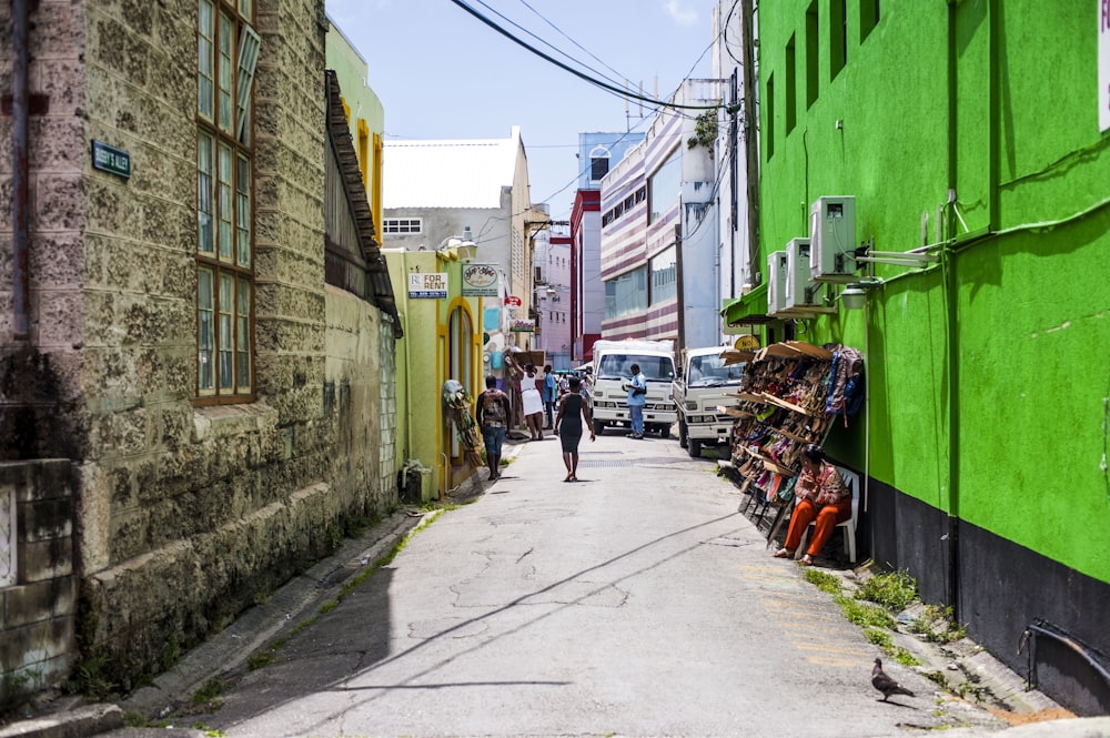 a man walking down a street next to a green building