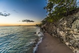 a sandy beach next to the ocean at sunset