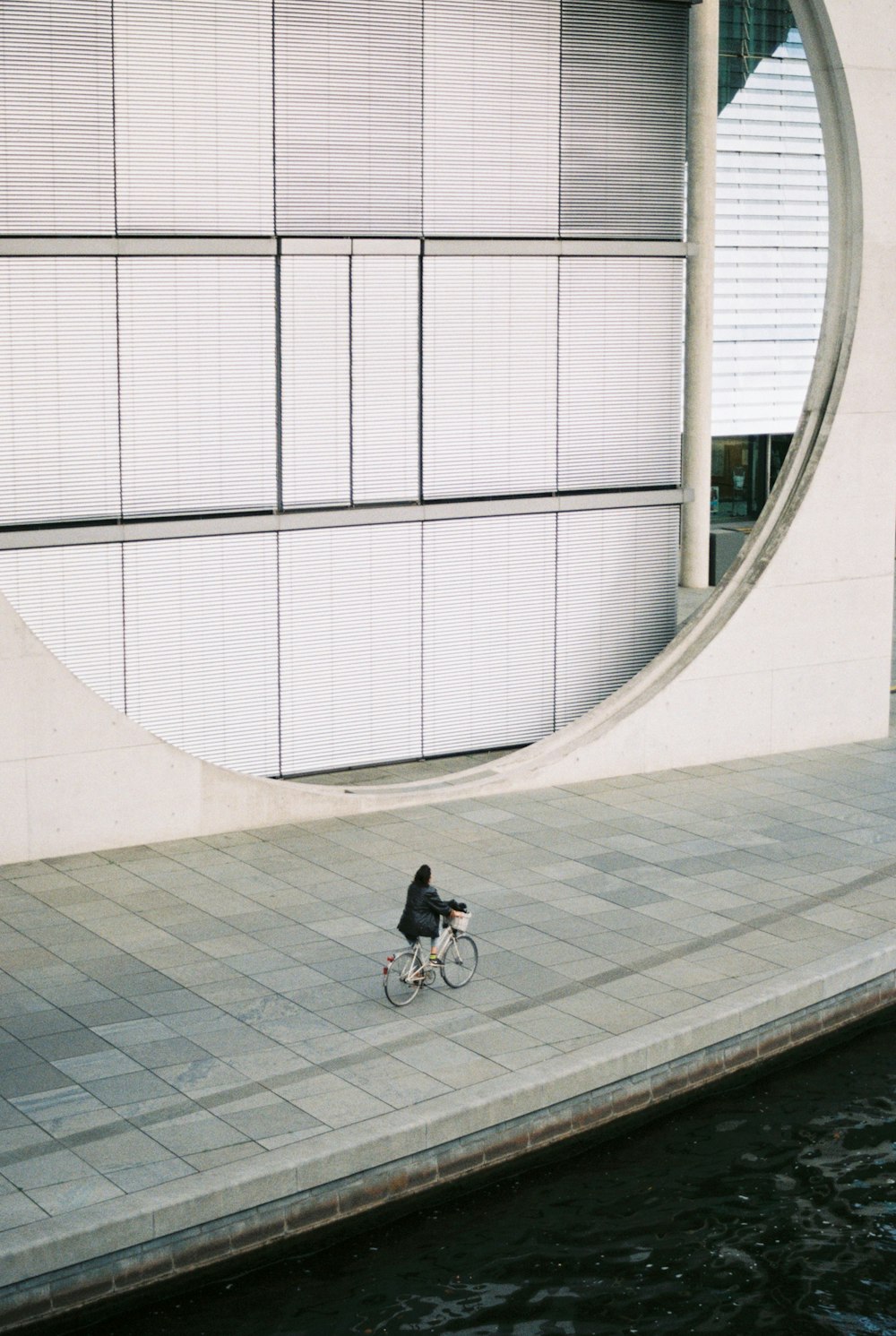 a man riding a bike down a sidewalk next to a body of water