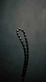 Close-up of an ancient Harappan bead necklace glowing softly against a dark background.