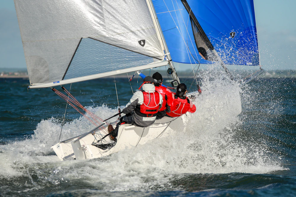 A high performance skiff planing fast with a colourful spinnaker and spray flying