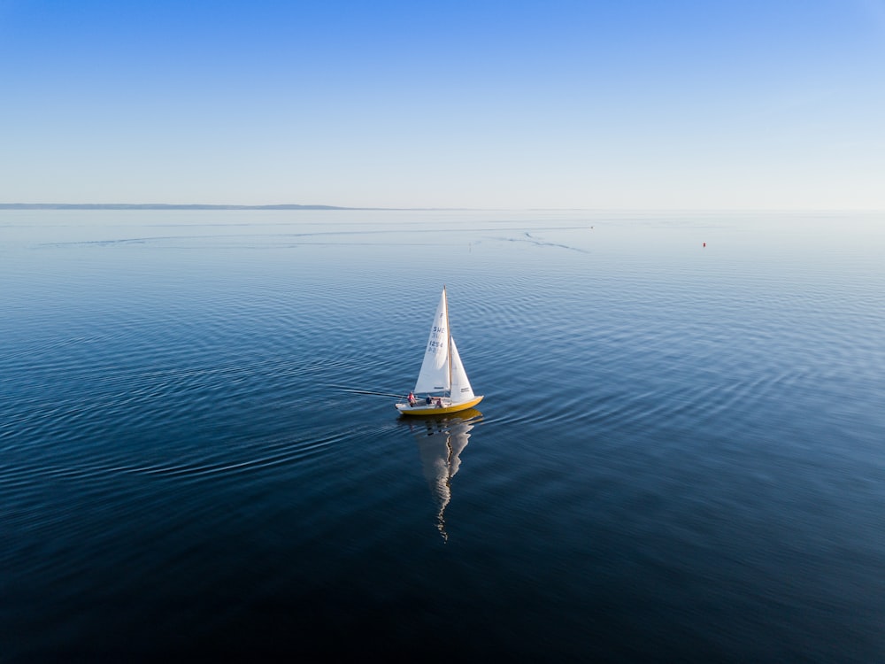 un petit voilier flottant sur un grand plan d’eau