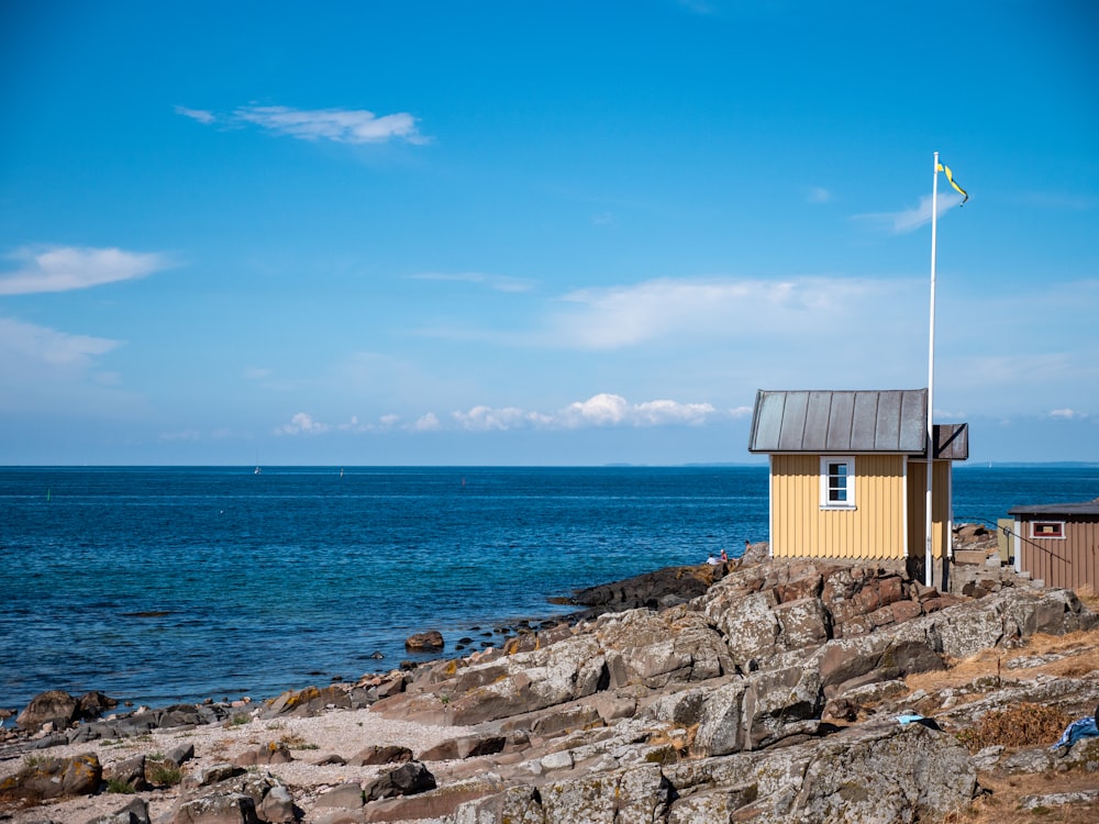 a small yellow building sitting on top of a rocky beach