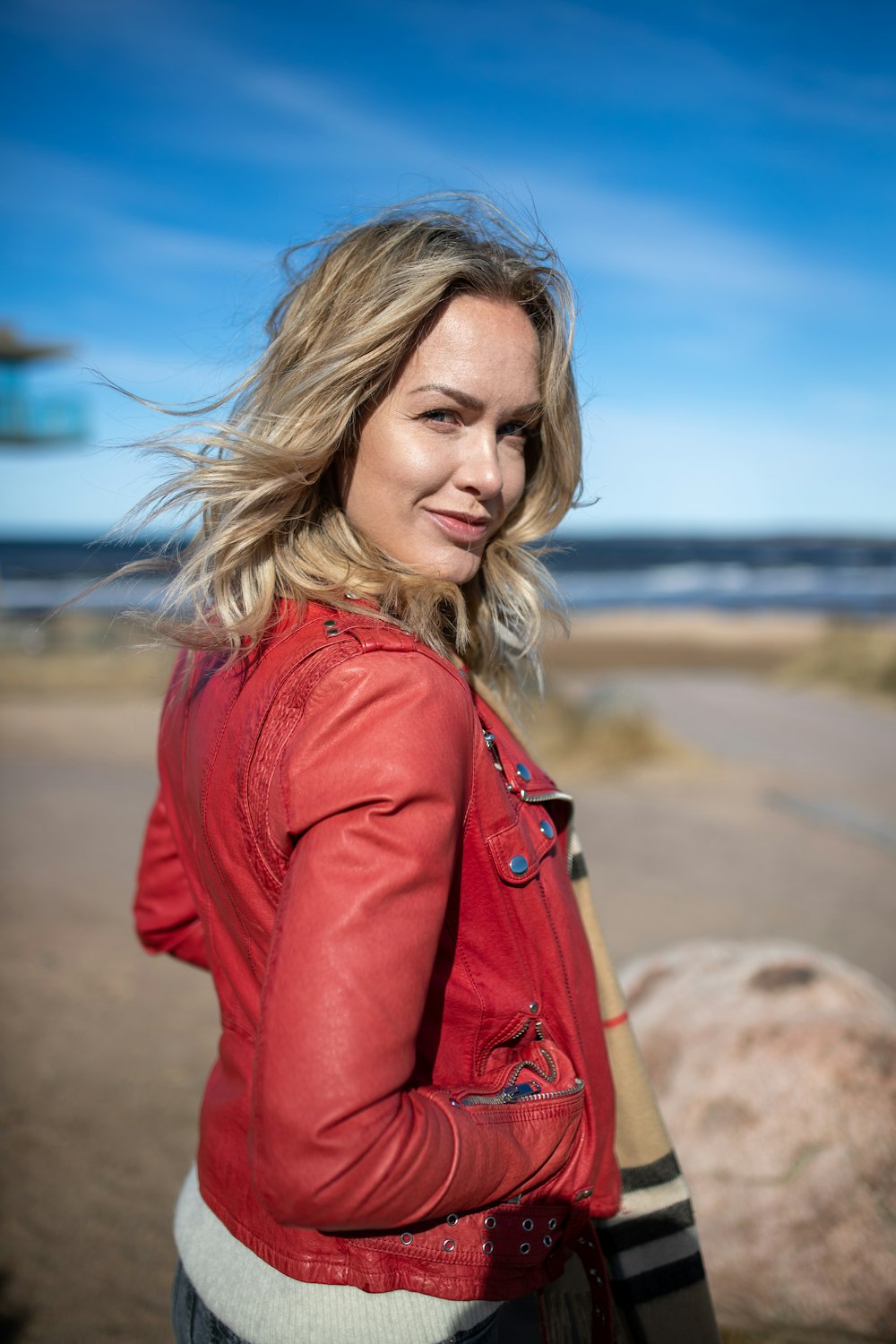 a woman in a red jacket is standing on the beach