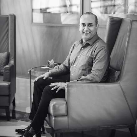 A calm and confident man smiling while sitting comfortably in a cozy room.