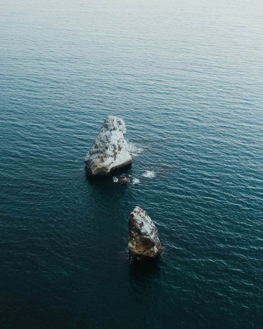 two large rocks in the middle of a body of water