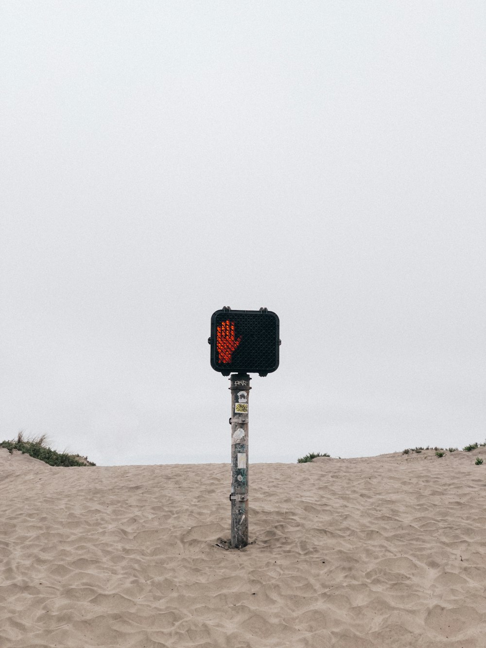 a traffic light sitting on top of a sandy beach