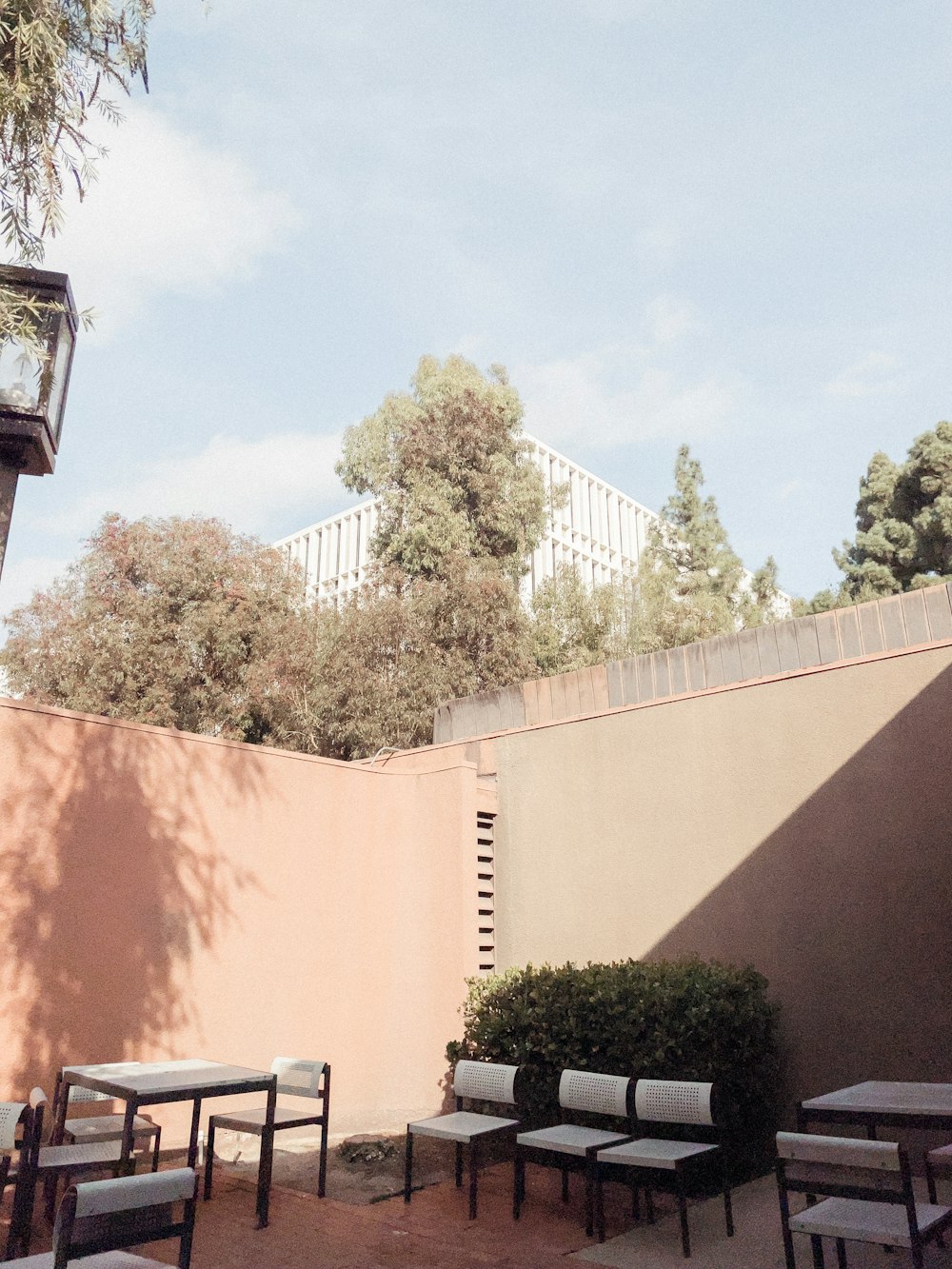 a patio with tables and chairs next to a wall