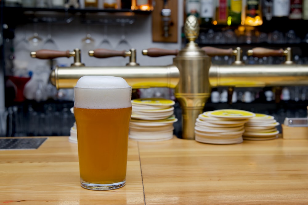 a glass of beer sitting on top of a wooden table