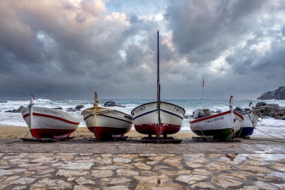 three boats sitting on the shore of a beach
