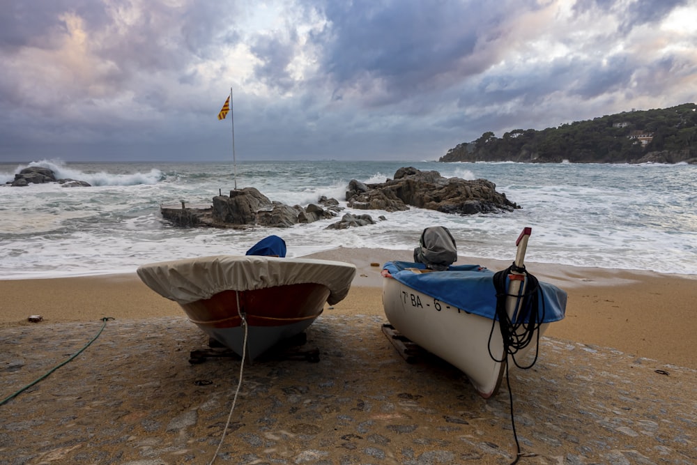 a couple of boats sitting on top of a sandy beach