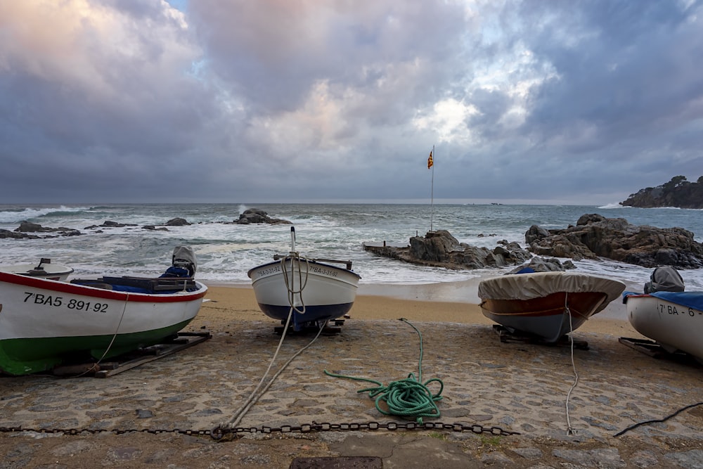 a couple of boats sitting on top of a sandy beach