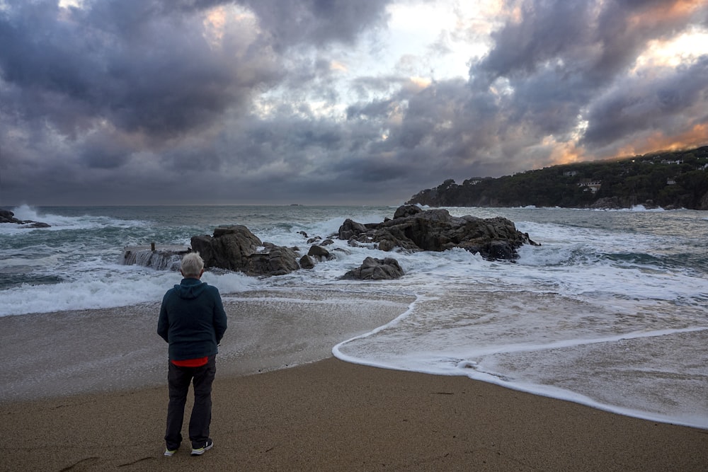 Eine Person, die an einem Strand steht und auf den Ozean schaut