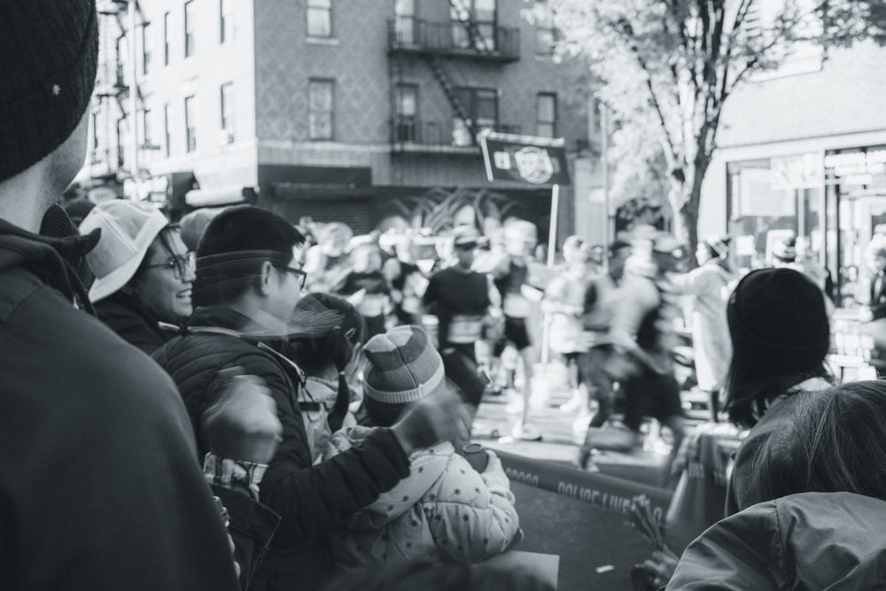 a crowd of people walking down a street next to tall buildings