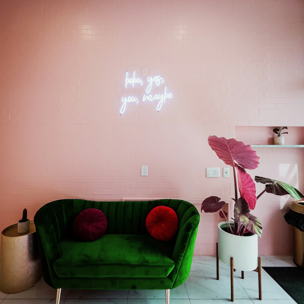 a living room with a green couch and a pink wall