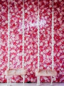 two white chairs sitting in front of a pink flower wall