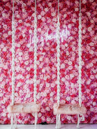 two white chairs sitting in front of a pink flower wall