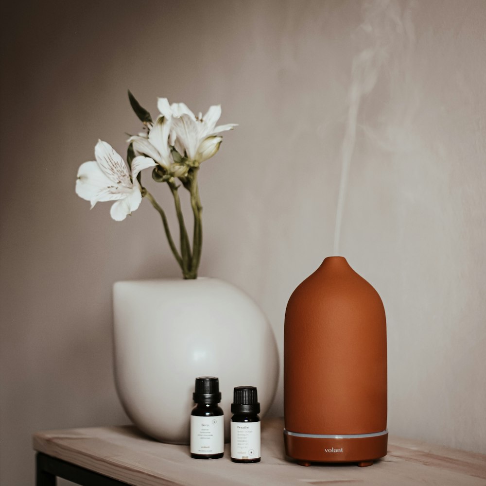 a vase with a flower and two bottles of essential oils on a table
