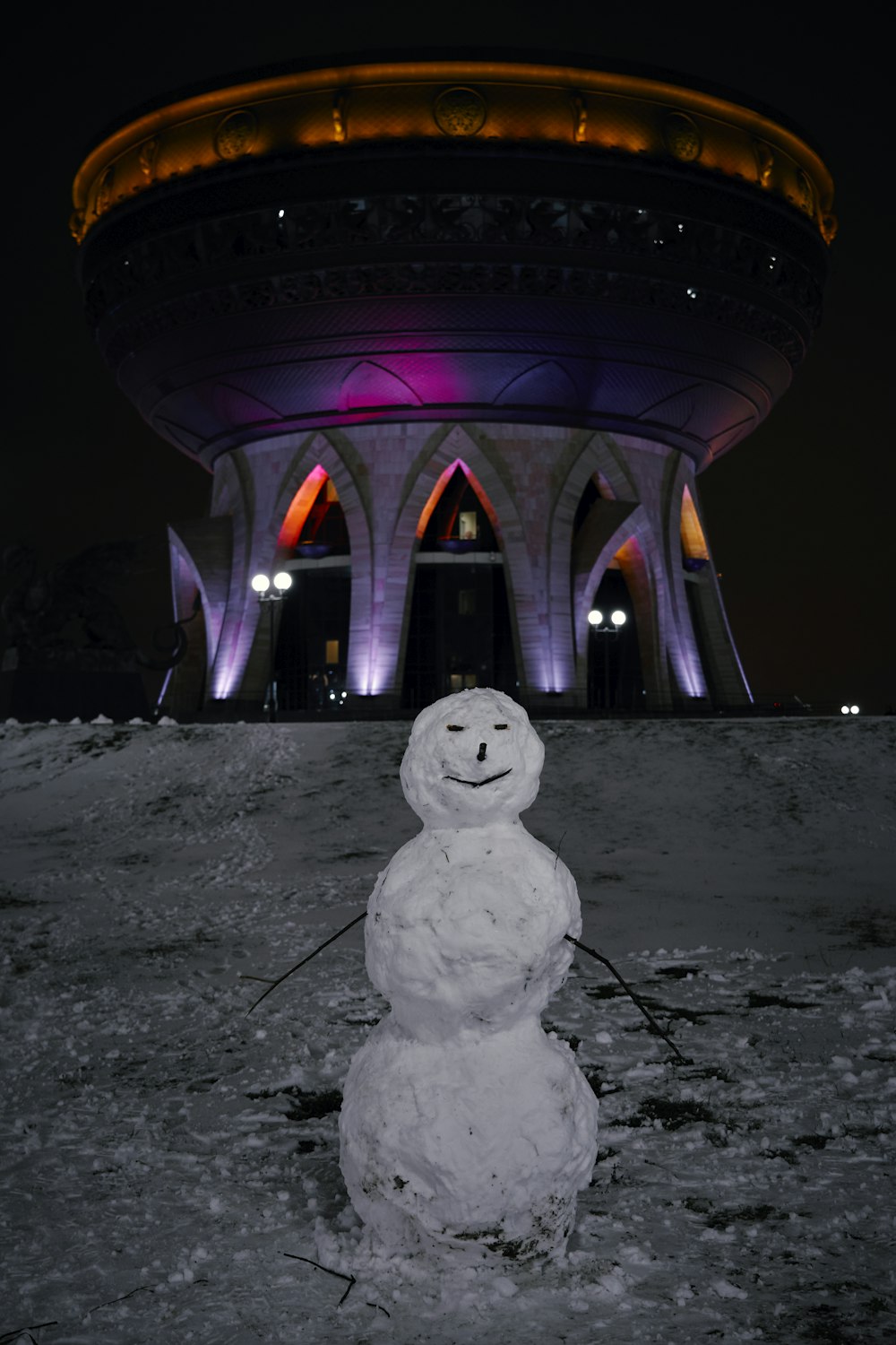 Un bonhomme de neige se tient devant un immeuble