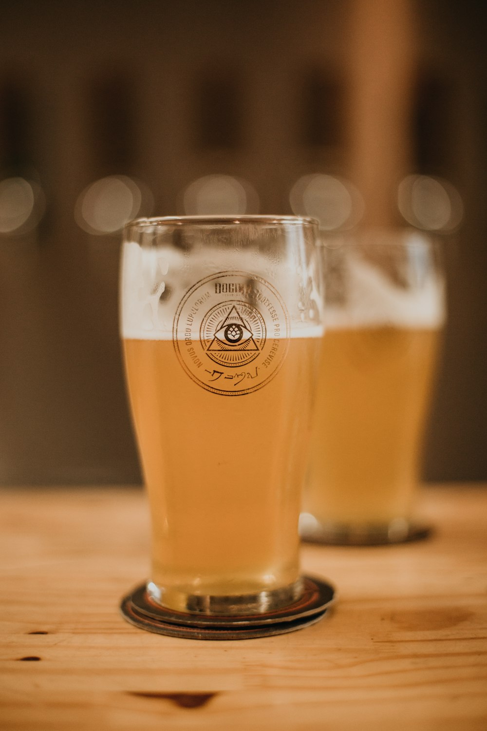 two glasses of beer sitting on top of a wooden table