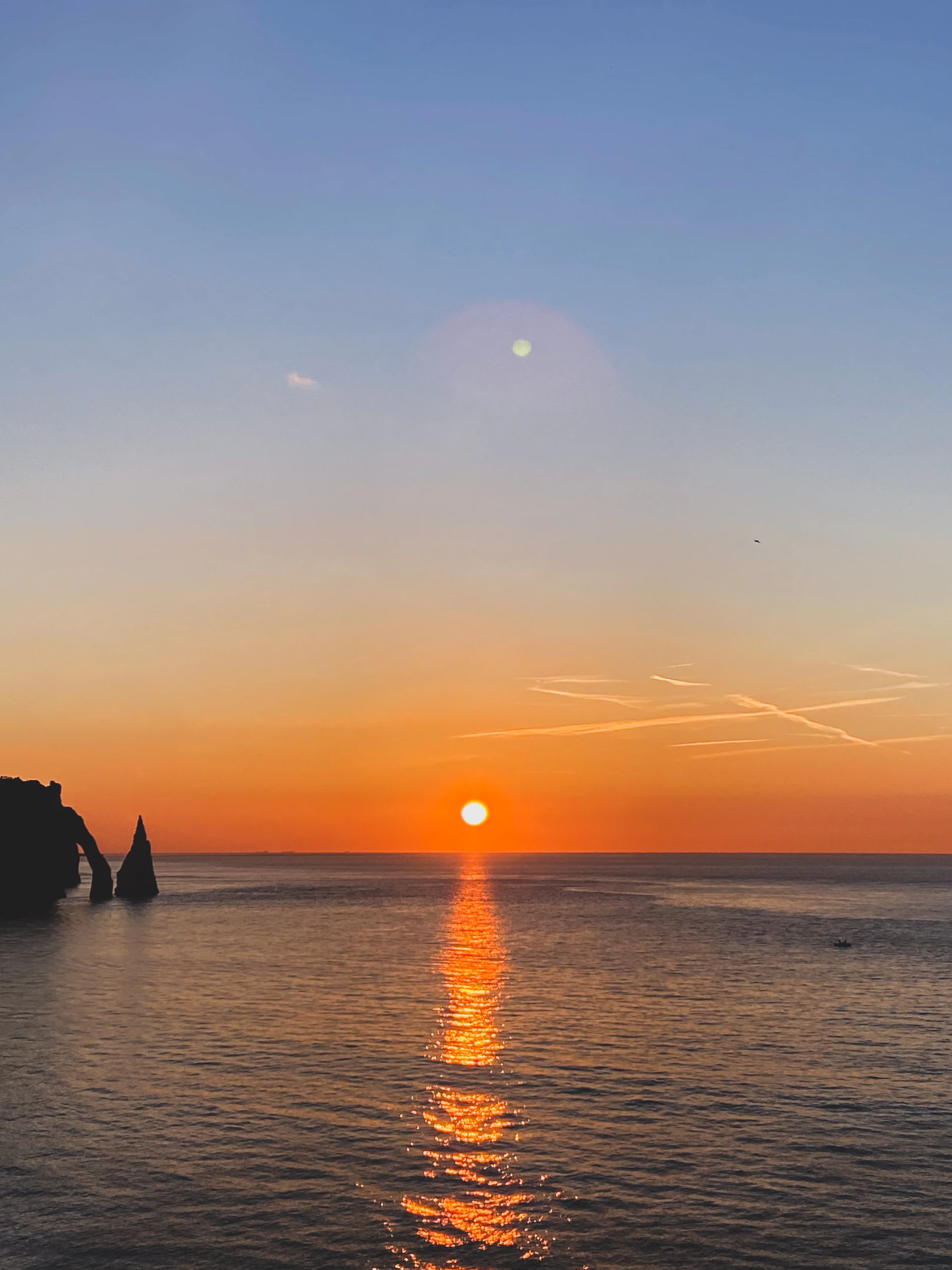 the sun is setting over the water off the coast