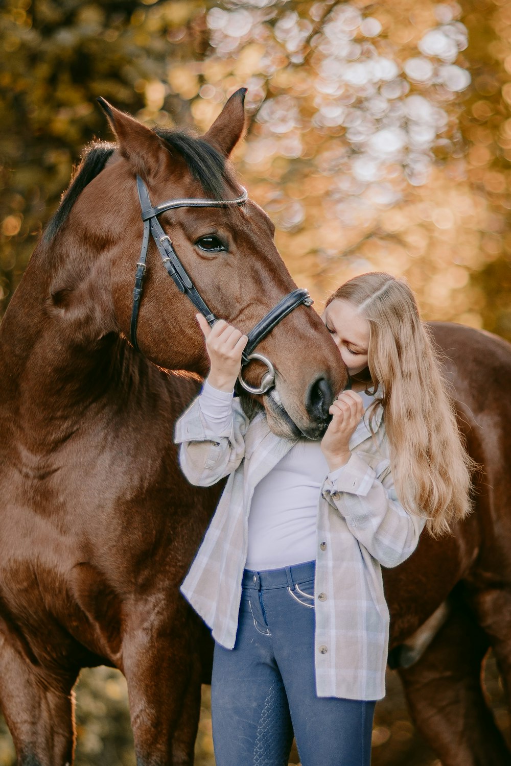 a woman standing next to a brown horse