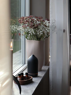 a vase filled with flowers sitting on a window sill