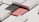 A geometric composition featuring rectangular and square shapes in a minimalist style. The image includes a black, textured rectangle alongside a smooth, red rectangle, surrounded by light gray structures that add a three-dimensional effect with shadows.