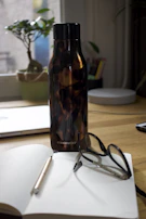 A Frostara thermos standing tall on a desk next to a laptop and notebook.