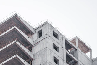 Industrial concrete factory with workers assembling premolded structures under a cloudy sky.