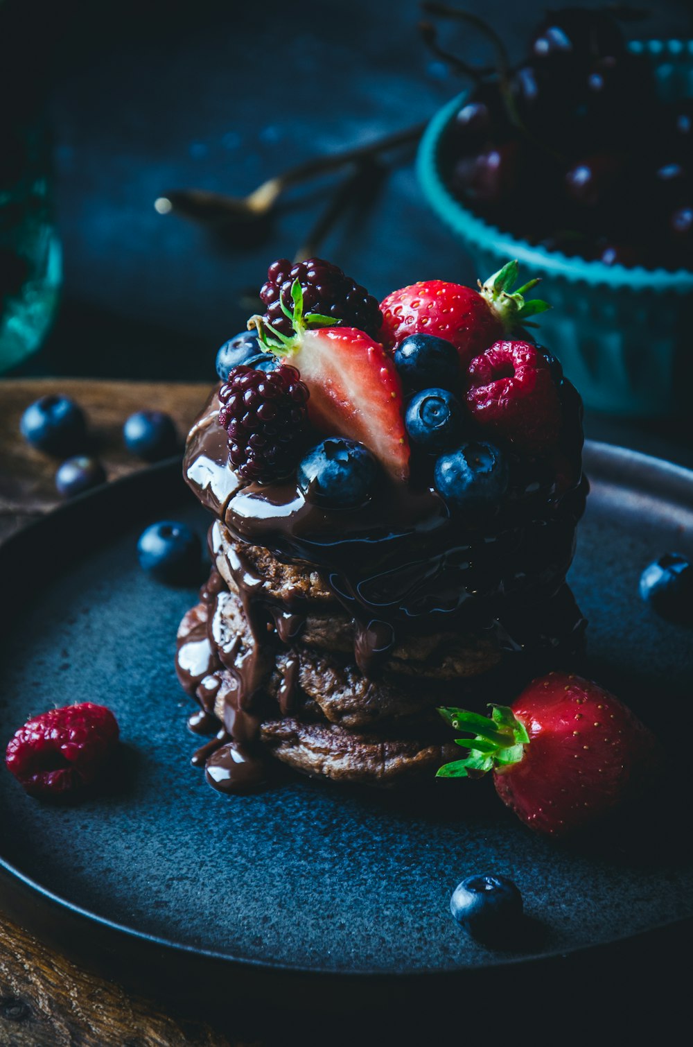 a stack of pancakes topped with berries and chocolate