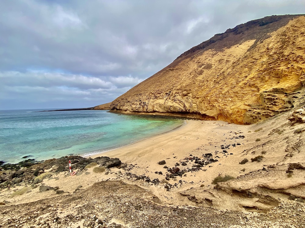 a sandy beach next to the ocean under a cloudy sky