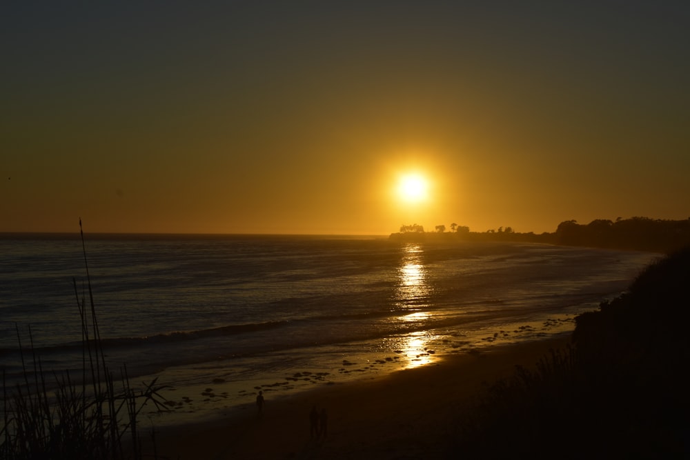 the sun is setting over the ocean on the beach