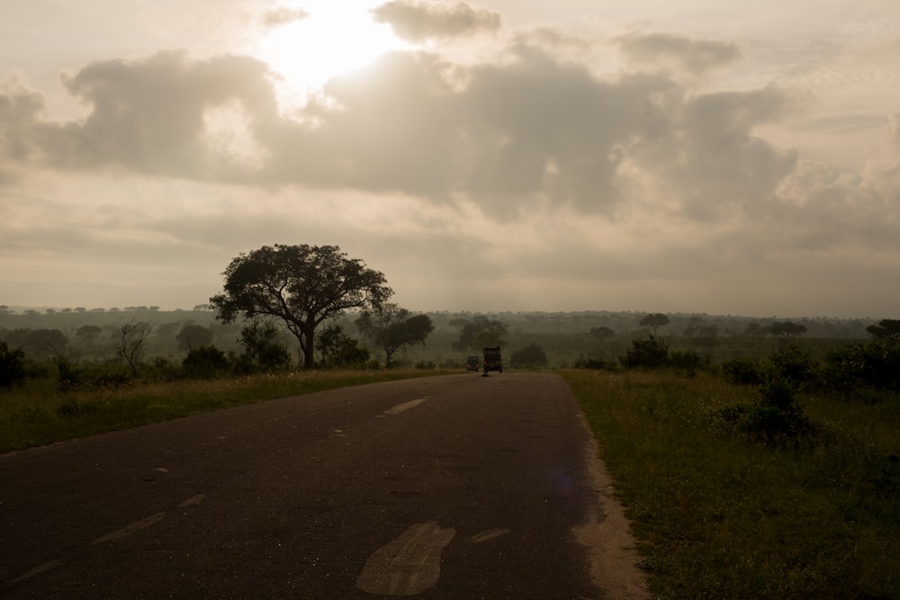 the sun shines through the clouds over a rural road